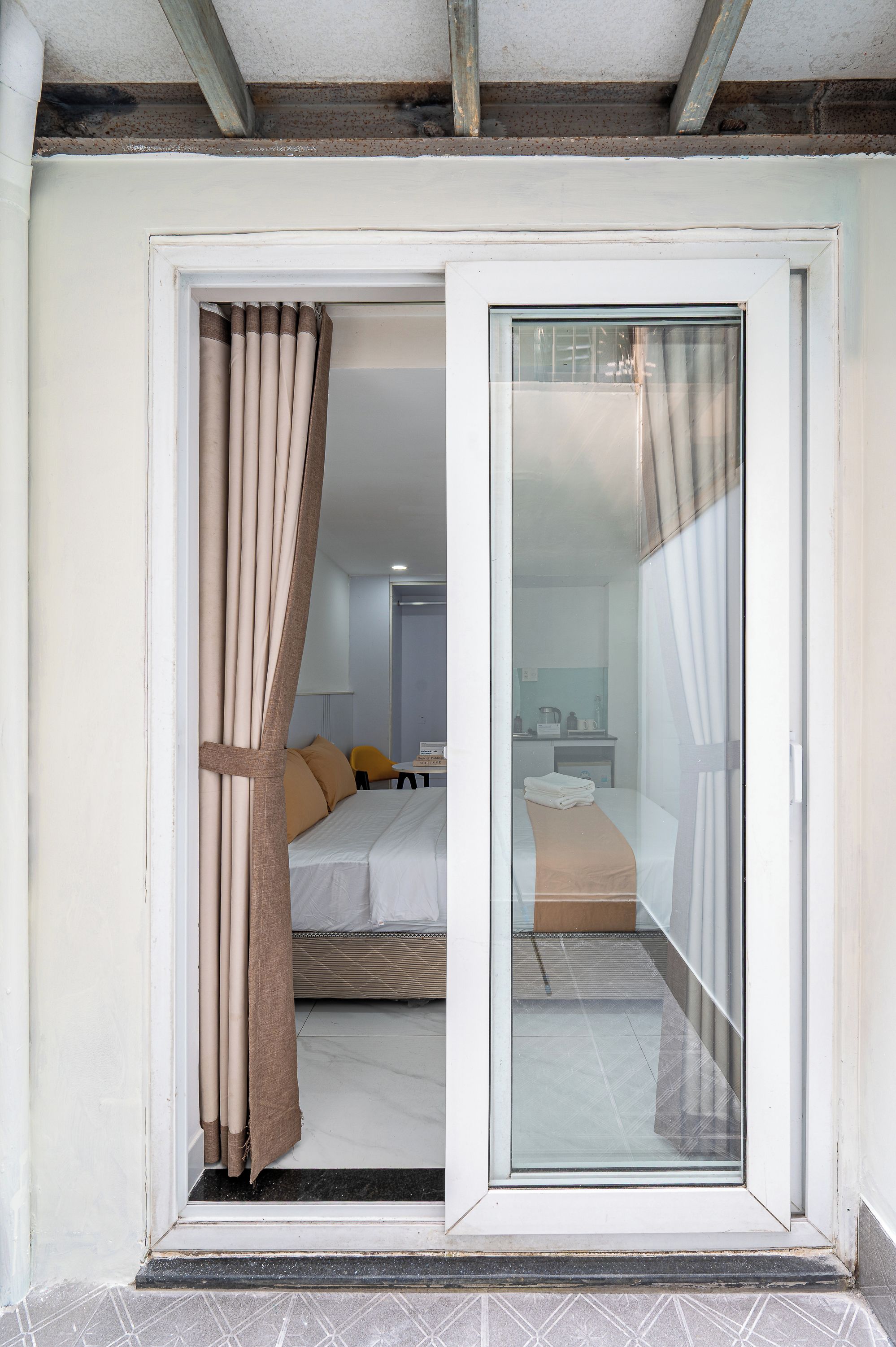 Quarto de hotel com uma cama, uma mesinha e uma cadeira.