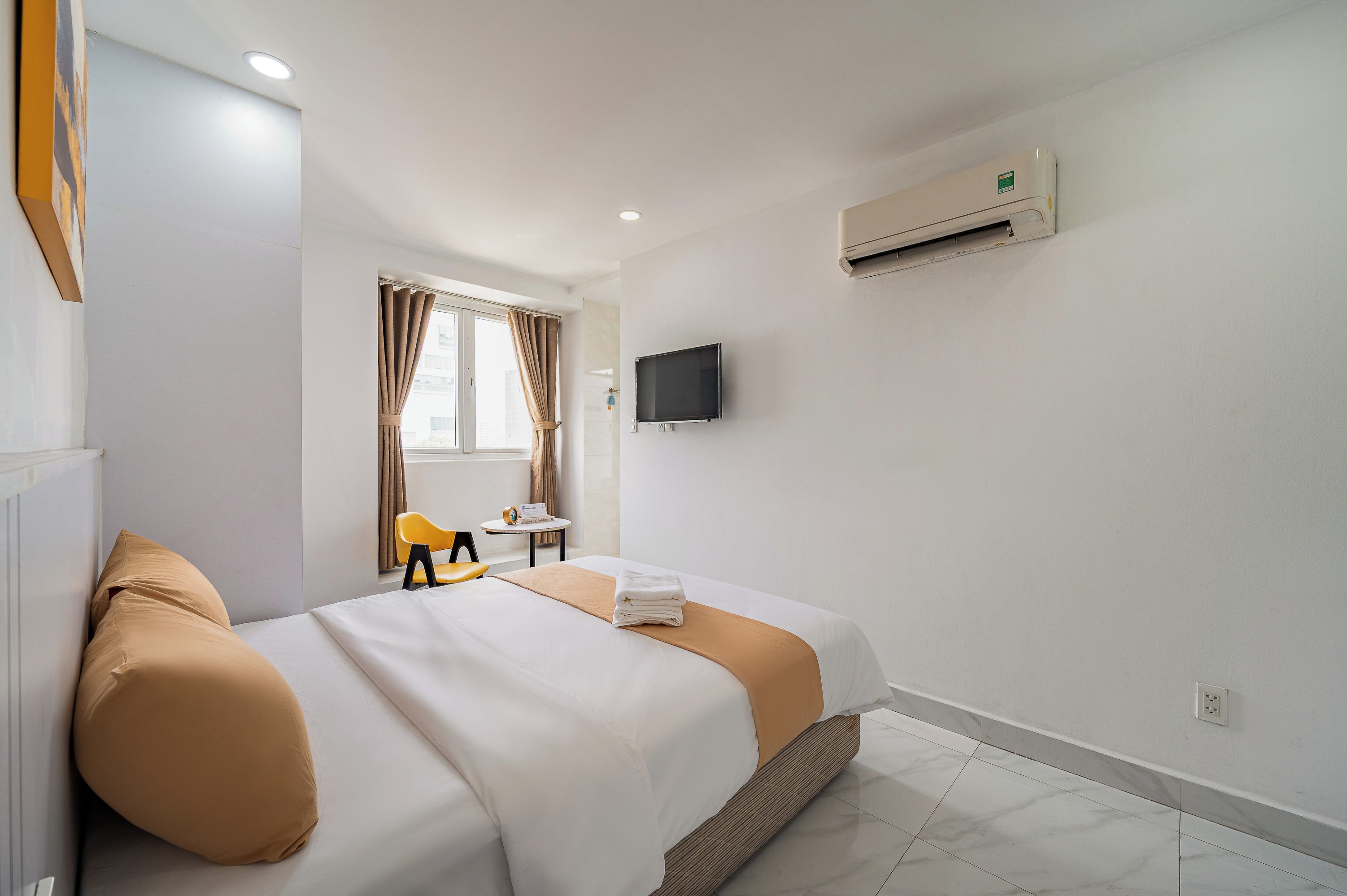 Una habitación de hotel con una cama, un televisor montado en la pared y un equipo de aire acondicionado.