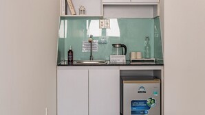 A compact kitchenette with a small refrigerator, a coffee maker, and a tea kettle. - Cozrum Homes - The Ivory House (Tan Hung)