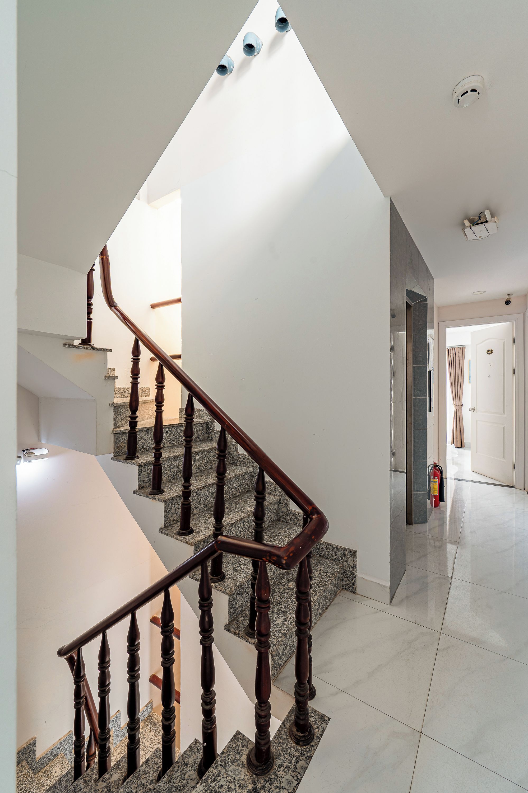 Un interior moderno con una escalera de madera, un tragaluz y un diseño minimalista y limpio.