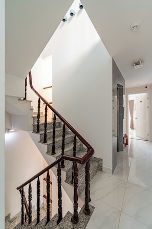 A modern interior with a wooden staircase, a skylight, and a clean, minimalist design. - Cozrum Homes - The Ivory House (Tan Hung)
