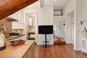 A modern kitchen with a flat-screen TV, wooden flooring, and a view of the living area. - Apartment 'Piranesi 45' with Wi-Fi and Air Conditioning (Milano)