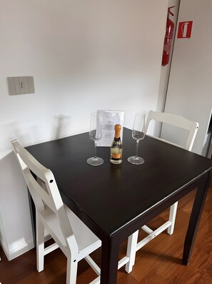 Een zwarte tafel met twee witte stoelen, een fles champagne en twee lege glazen.