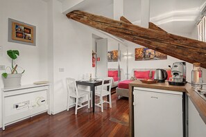 Habitació d'hotel moderna amb escala de fusta, zona de dinar i petita cuina.