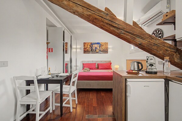 Een kleine hotelkamer met een bed, een eettafel en een kitchenette.