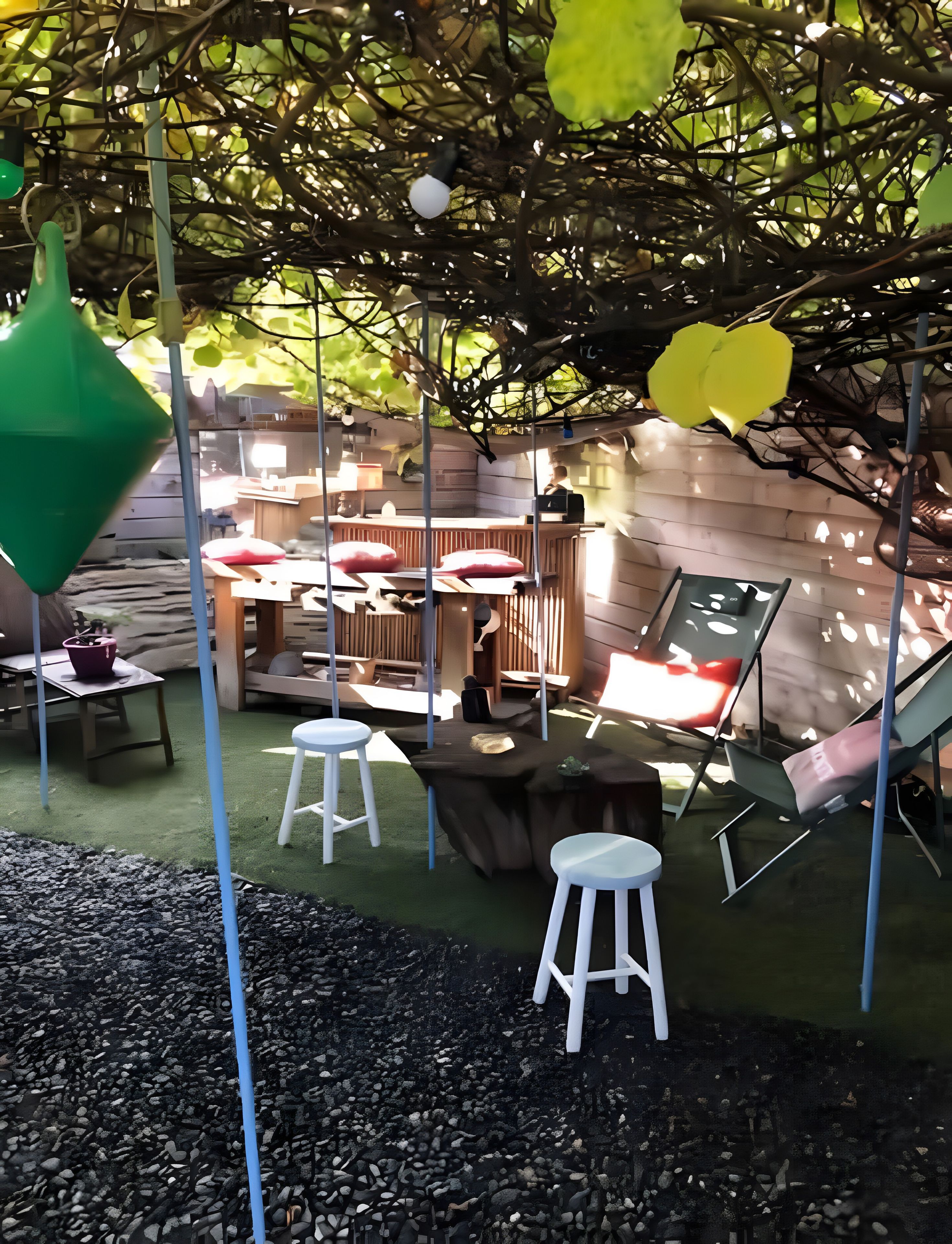 Un espacio al aire libre con mesas y sillas, rodeado de follaje e iluminación decorativa.