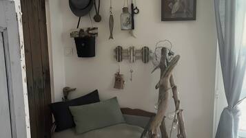 A cozy room with a sofa, a decorative wall hanging, and a rustic wooden sculpture.