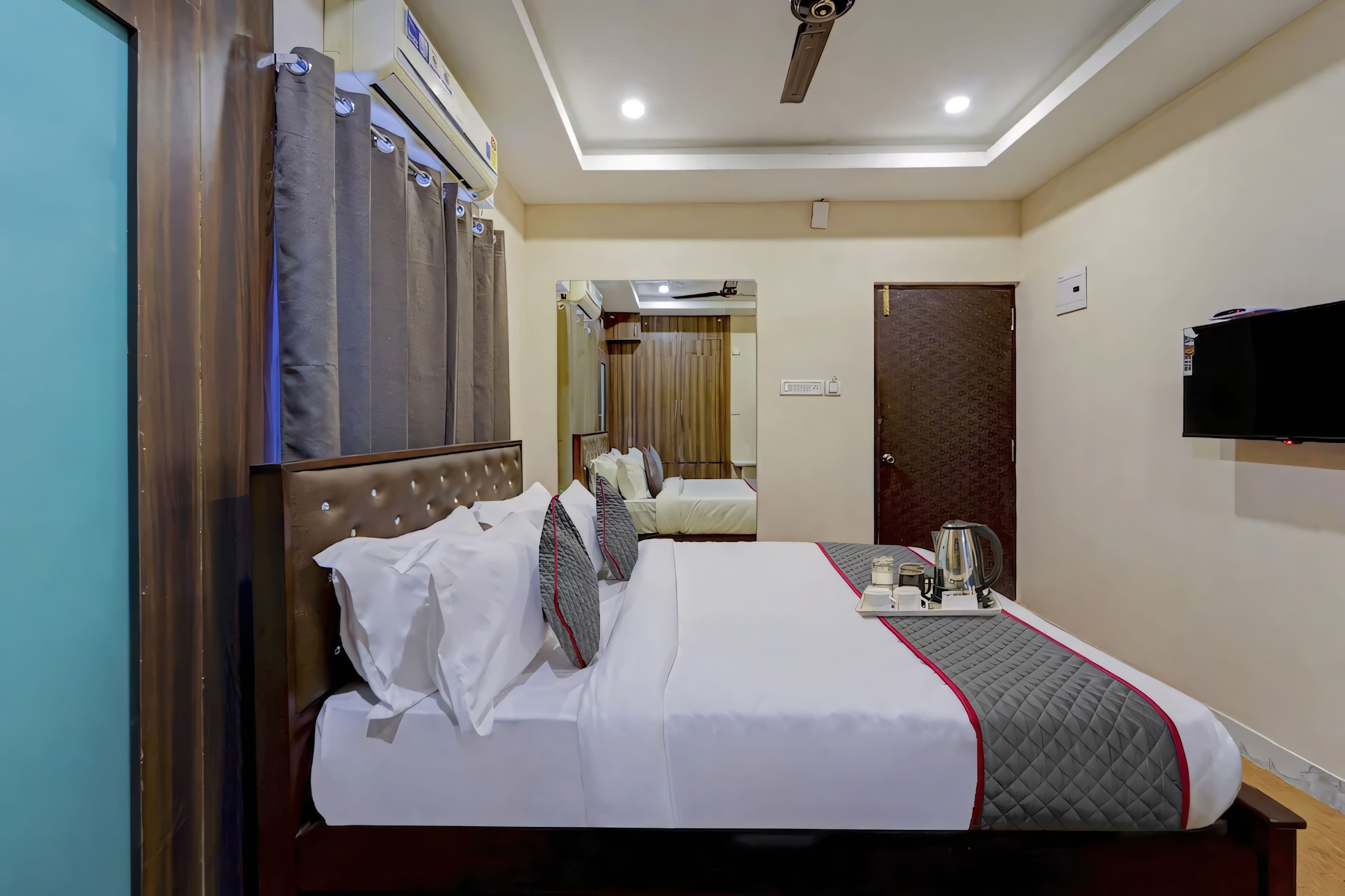 Una habitación de hotel con una cama, una mesita de noche y un televisor montado en la pared.