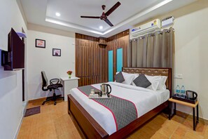 A hotel room with a bed, a desk, a chair, a ceiling fan, an air conditioning unit, and a water dispenser. - GSILVER HOTELS NUNGAMBAKKAM (Chennai)