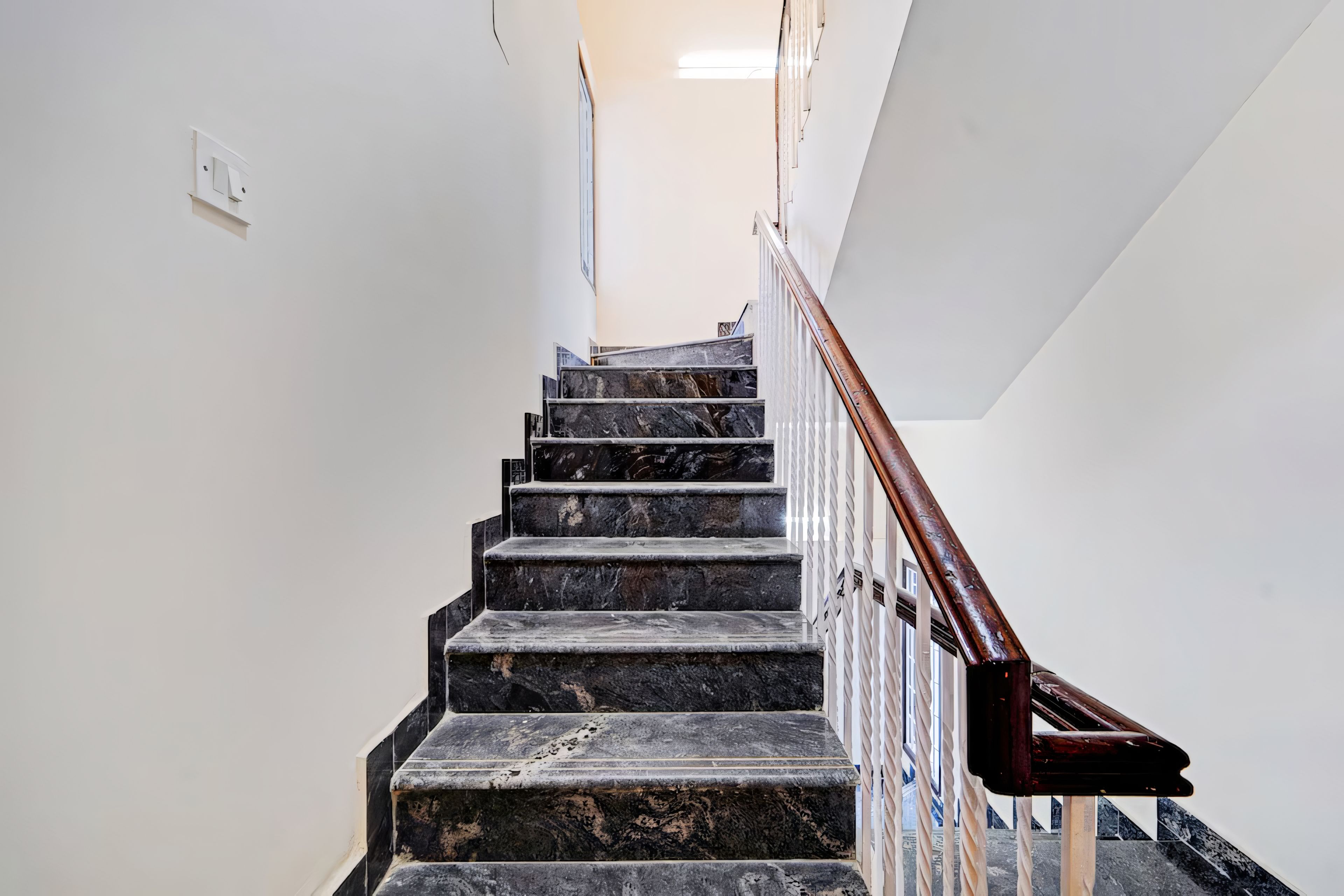 A staircase with marble steps and a wooden handrail.