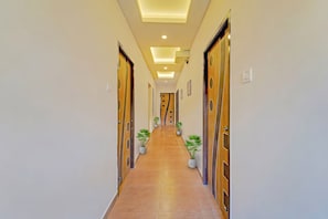 A hallway with wooden doors, potted plants, and recessed lighting.