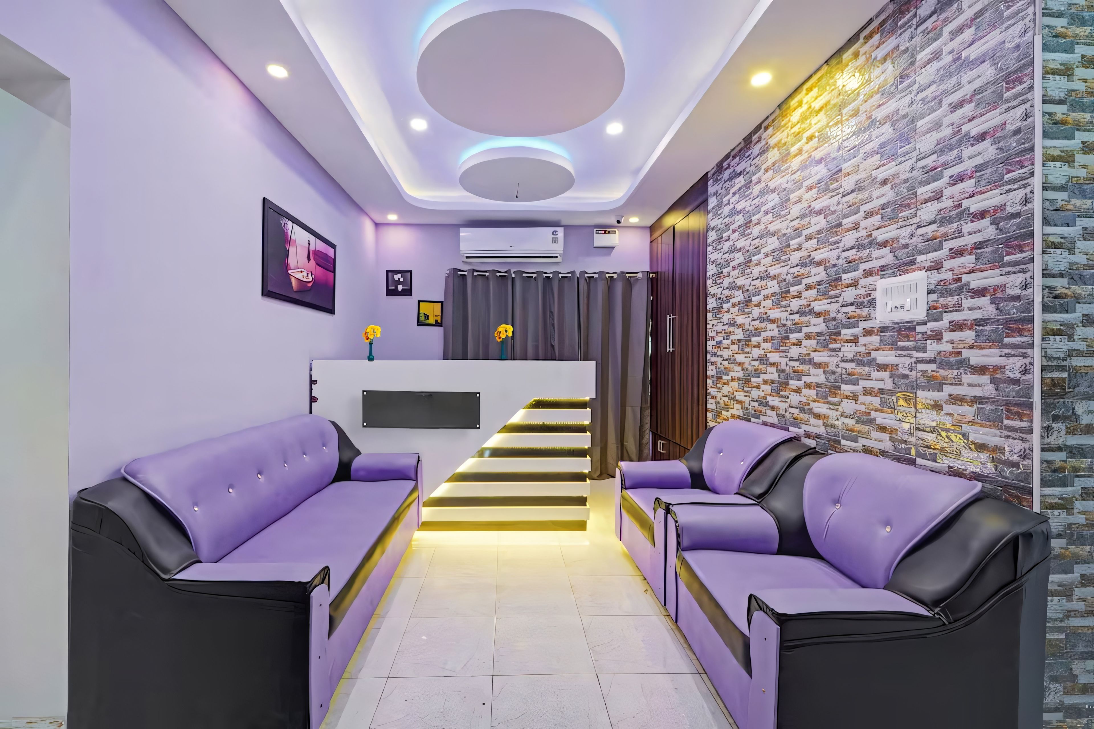 Un interior moderno con un mostrador de recepción, sofás morados, una escalera y una pared con diseño.
