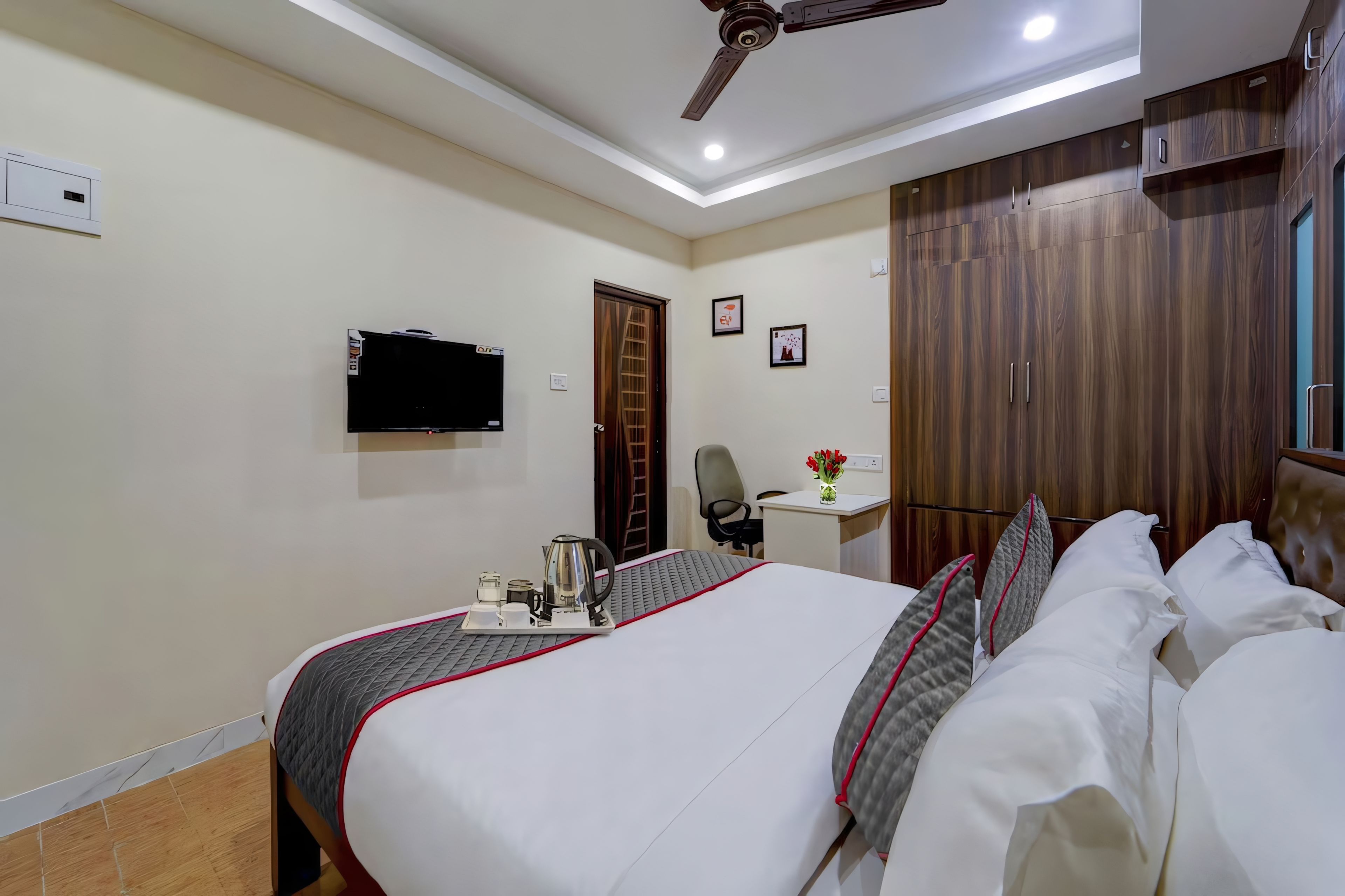 Una camera d'albergo con un letto, una scrivania, una sedia, una televisione e un armadio.