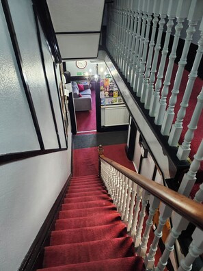 A staircase with a red carpet, white balusters, and a wooden handrail.