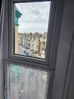 Una ventana con vista a casas escalonadas y coches estacionados.