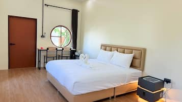 Quarto de hotel com cama, escrivaninha, cadeira, janela e porta.