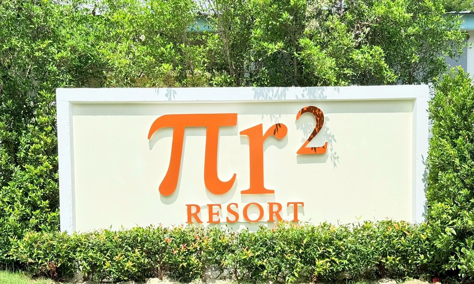 A sign for 'Pi2 Resort' with a white background and orange lettering.