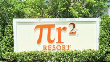 A sign for 'Pi2 Resort' with a white background and orange lettering.