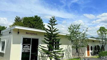 Edifício da recepção com uma placa, uma pequena árvore e um muro de pedra na frente.