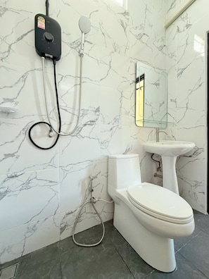 Ein Badezimmer mit Toilette, Bidet und einer an der Wand montierten Handbrause.