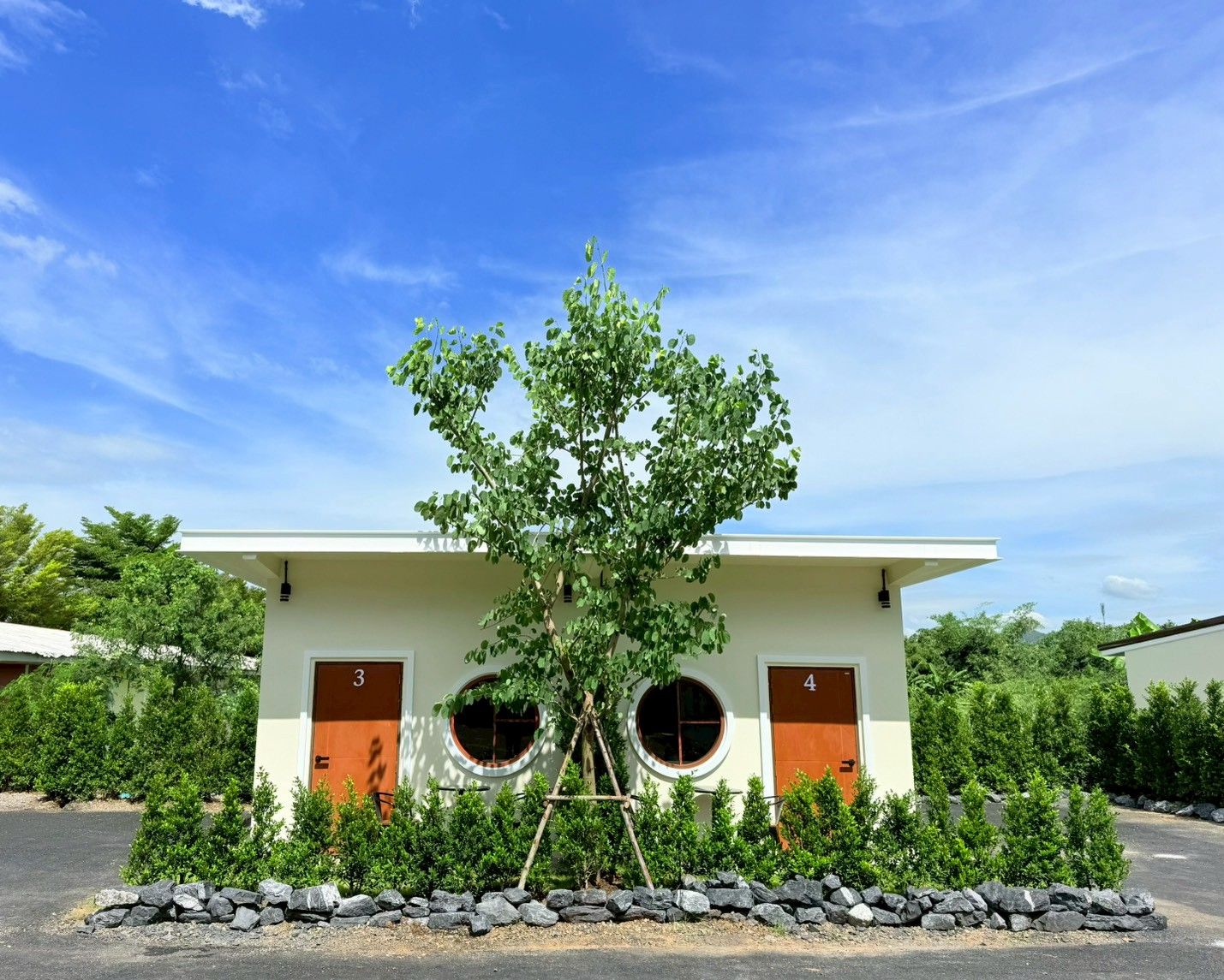 Un edificio moderno con dos puertas, números 3 y 4, y un árbol en la entrada.