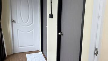 A hallway with a wooden floor, two doors, and a welcome mat.