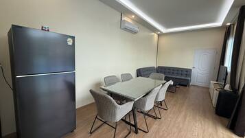 A compact living space with a kitchenette, a dining area with a table and chairs, a sofa, and a door.