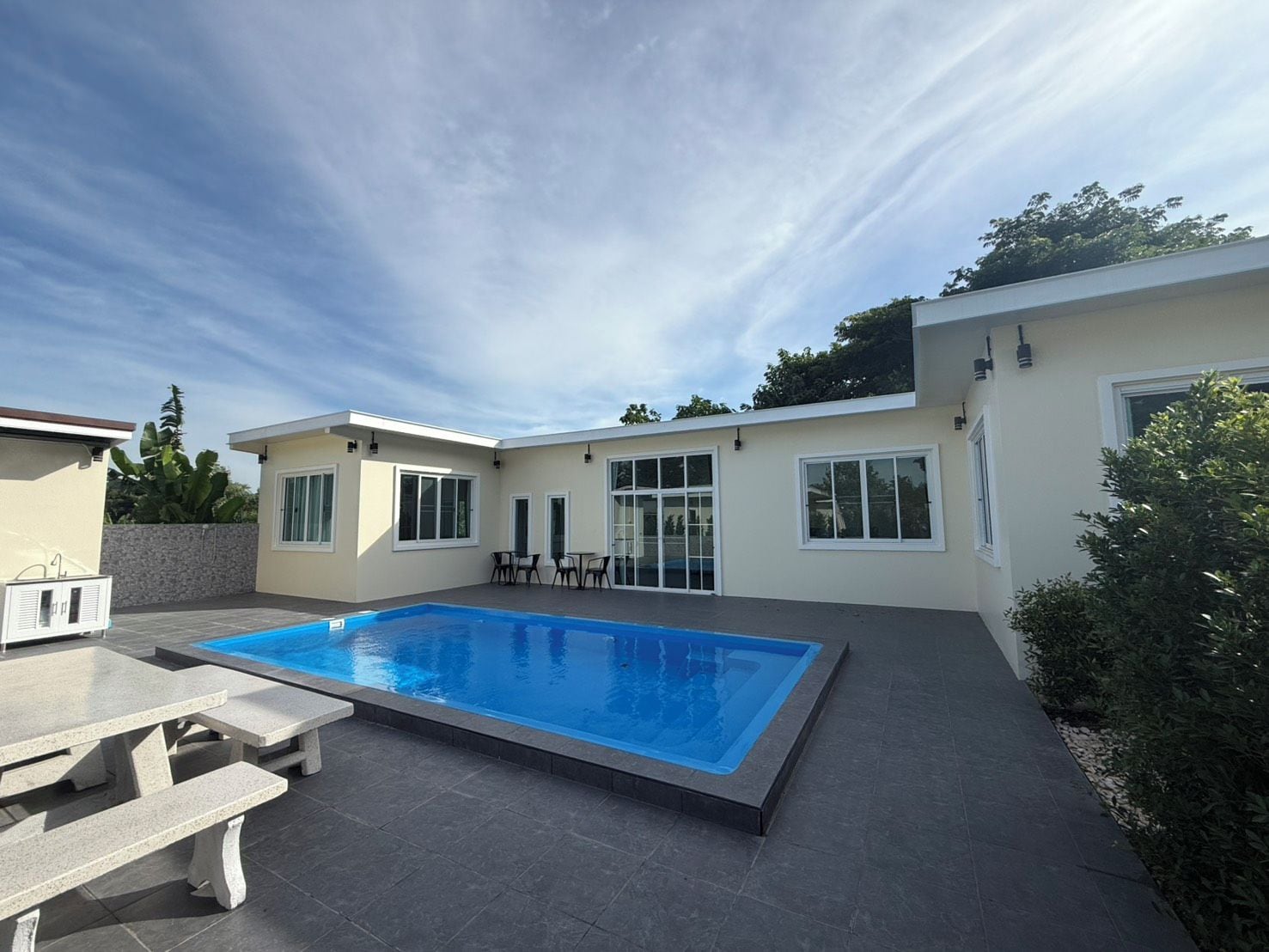 A modern house with a swimming pool, patio furniture, and a clear sky.
