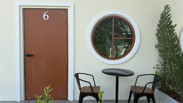 Una puerta con un número, un ventanal redondo y dos sillas frente a un edificio.