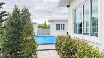 Um imóvel residencial com piscina, um caminho e uma casa com grandes janelas.