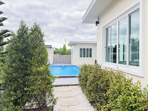 Una propiedad residencial con piscina, un camino y una casa con grandes ventanales.