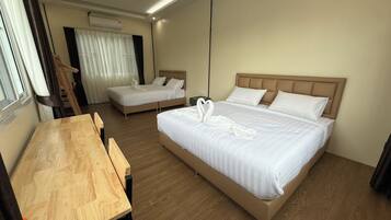 A hotel room with two beds, a wooden desk, and a window with curtains.