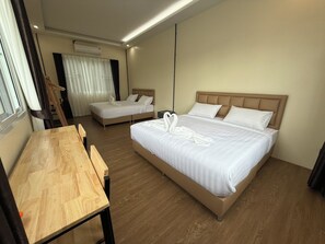 Habitación de hotel con dos camas, un escritorio de madera y una ventana con cortinas.