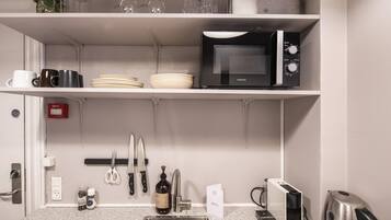 A kitchen with a microwave, sink, and various utensils.