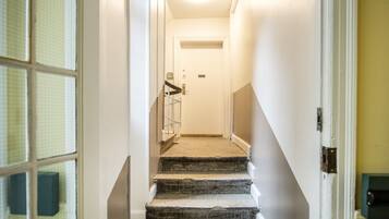 A carpeted staircase with a handrail, leading to a door with a keypad lock.