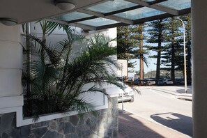A building entrance with a stone wall and a glass canopy. - Manly Beachfront 3BR, walk to cafes & dining (Manly)
