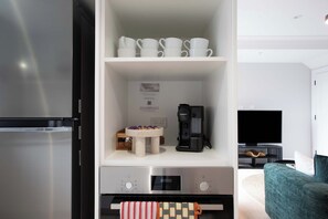 Uma cozinha moderna com máquina de café expresso integrada, moedor de café e micro-ondas.