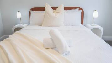 A neatly made bed with white linens, two bedside lamps, and two pillows.