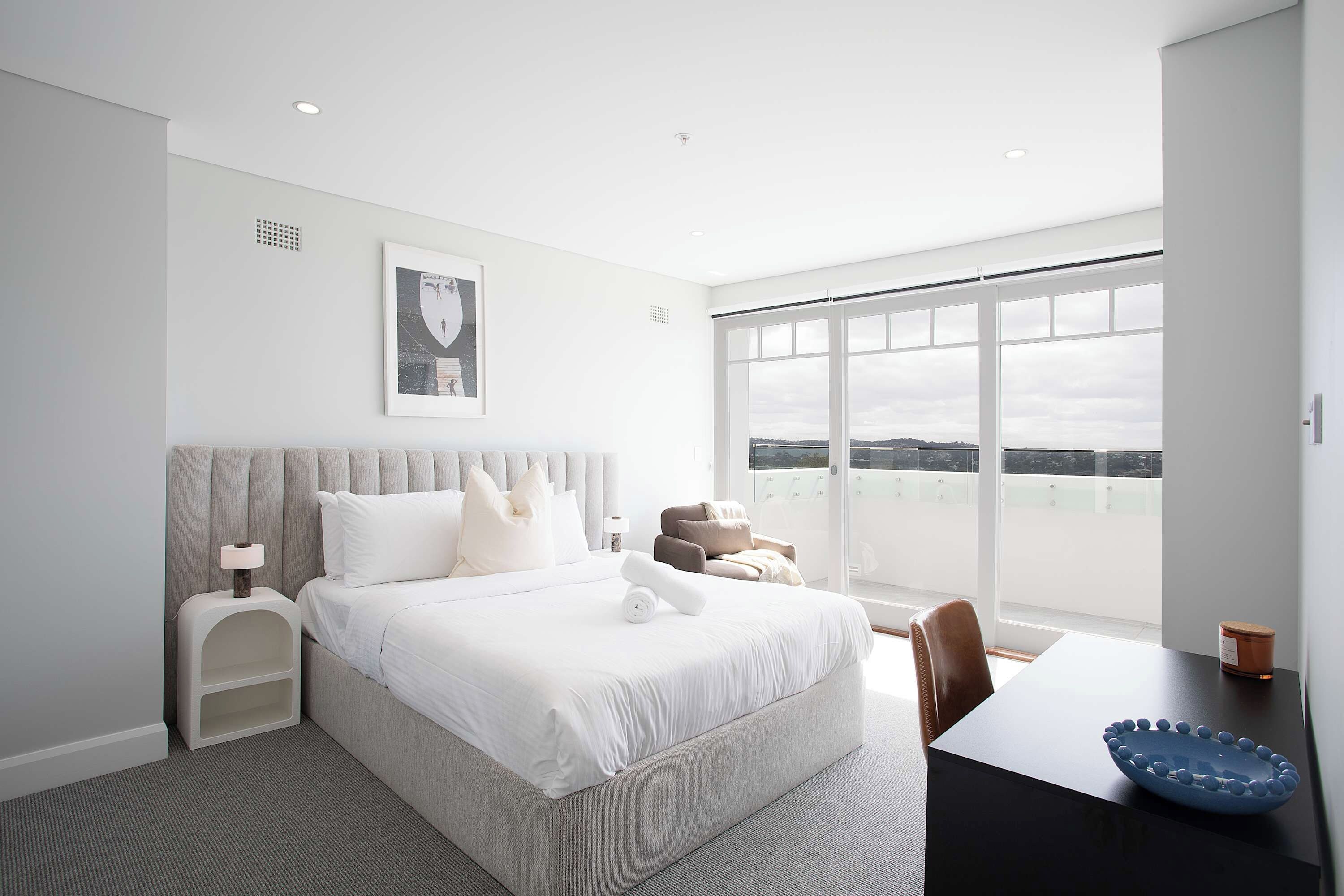 A modern hotel room with a large bed, a desk, and a view of the city.