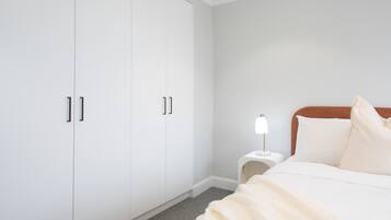 A bedroom with a bed, a nightstand, a lamp, and a wardrobe.