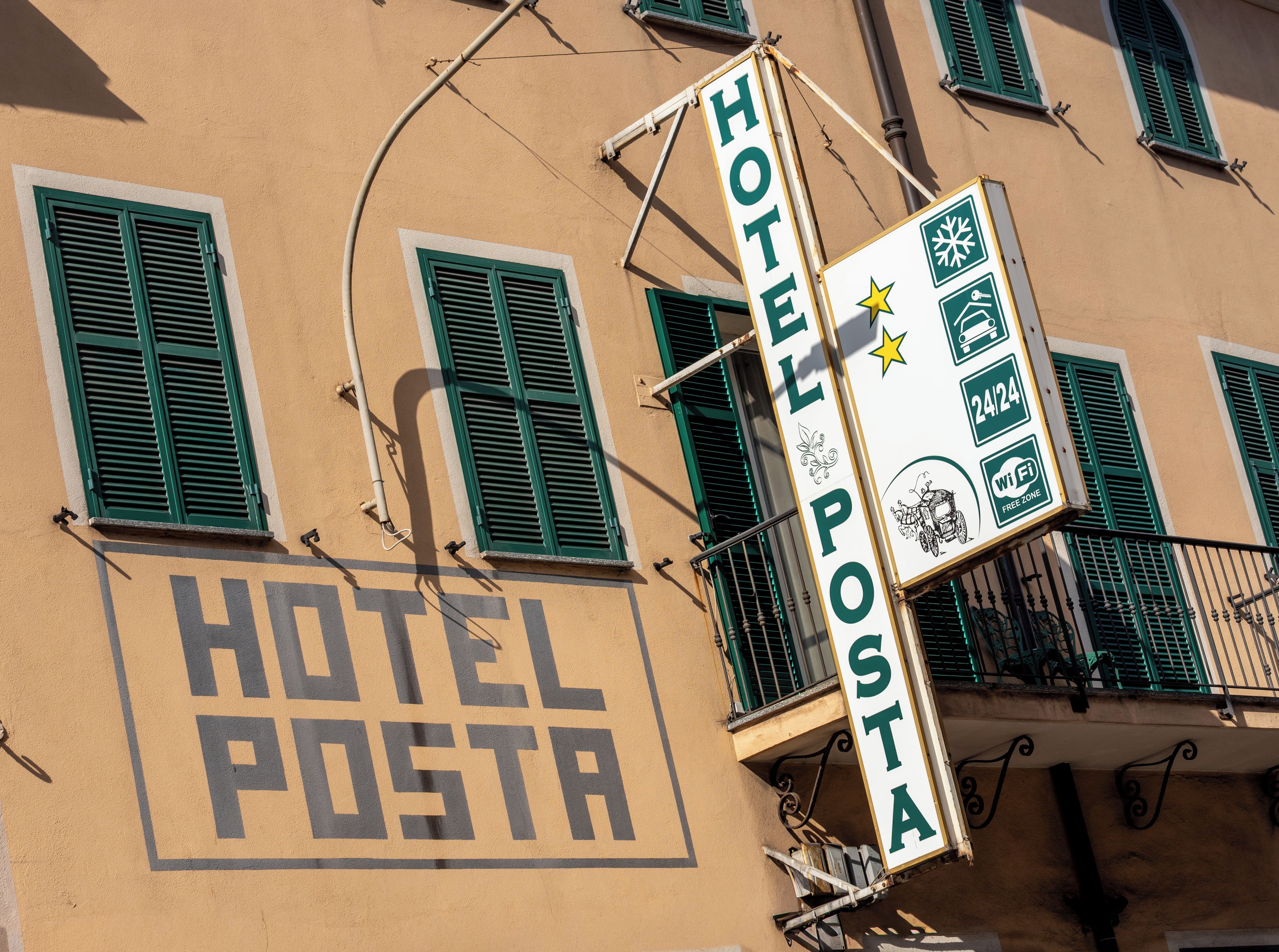Un edificio con un cartel que dice 'HOTEL POSTA' y otro indicando disponibilidad de '24/24' y 'WiFi'.