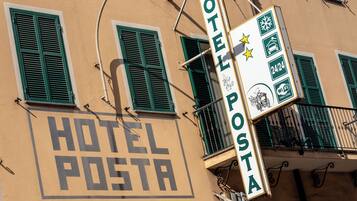 Un edificio con un cartel que dice 'HOTEL POSTA' y otro indicando disponibilidad de '24/24' y 'WiFi'.