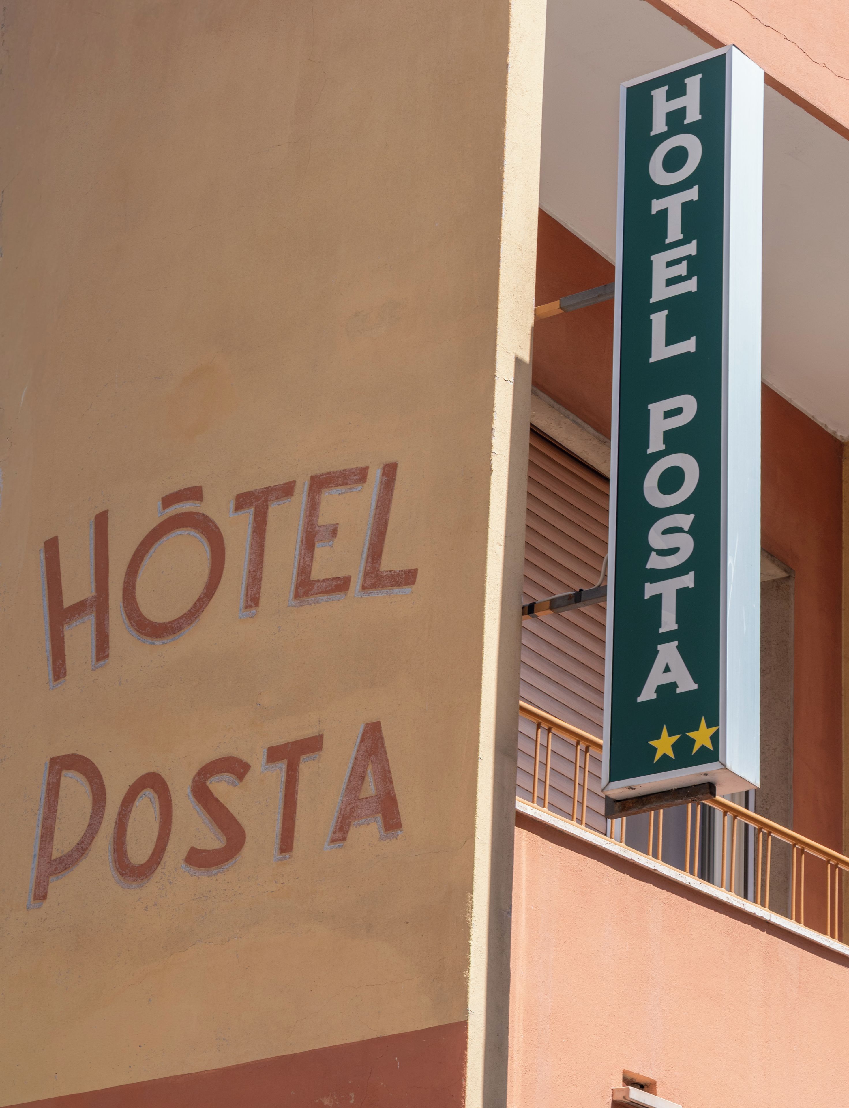 A building with a sign that reads 'HOTEL POSTA' and a smaller sign above it that says 'HOTEL POSTA' with two stars.