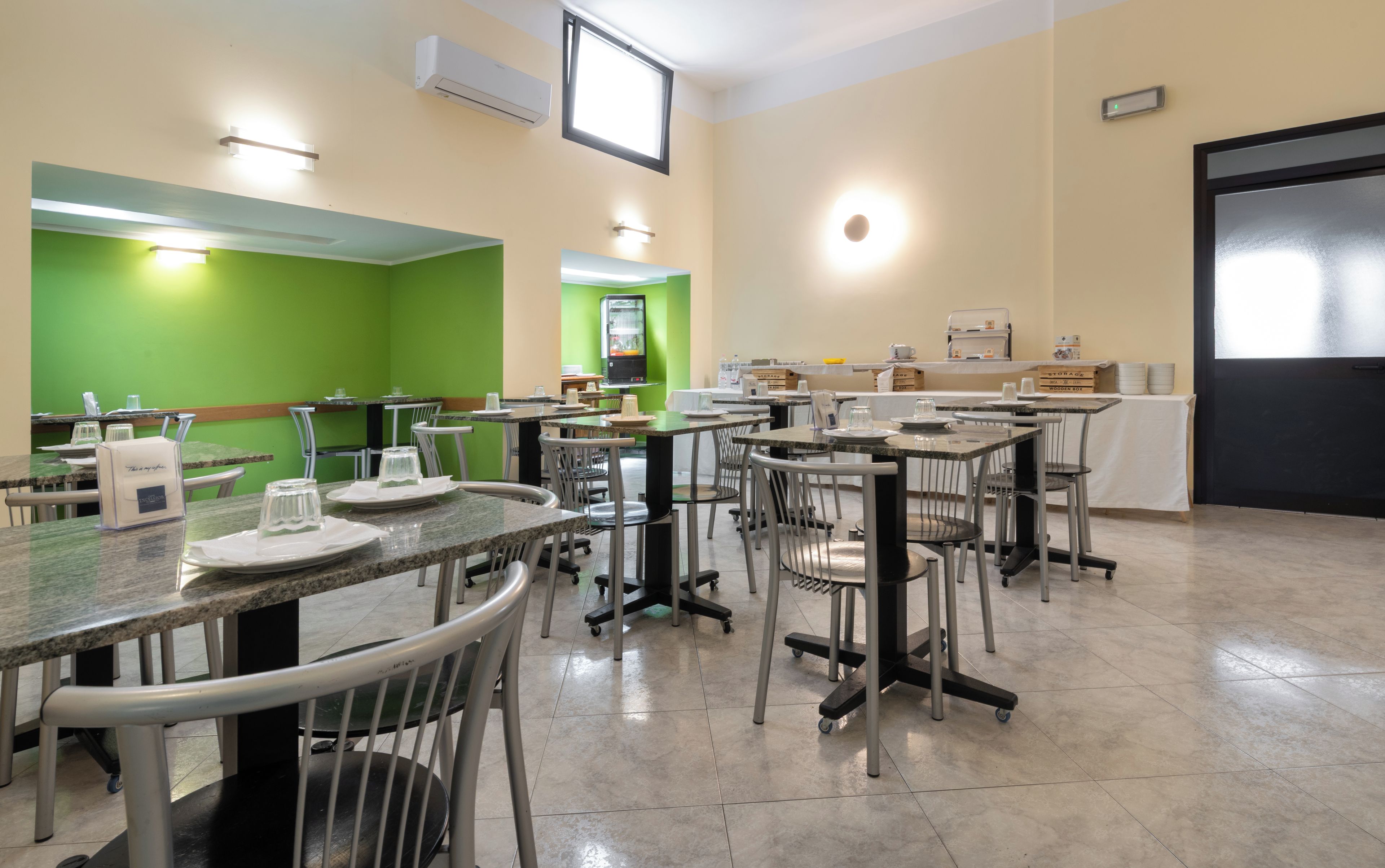 Un espace repas avec des tables et des chaises, un mur végétal et une porte.