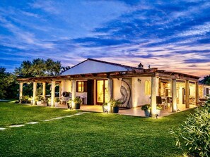 A two-story house with a covered patio, a garden, and a view of the sky. - Finca in Santa Magalida With Wifi (Santa Margalida)