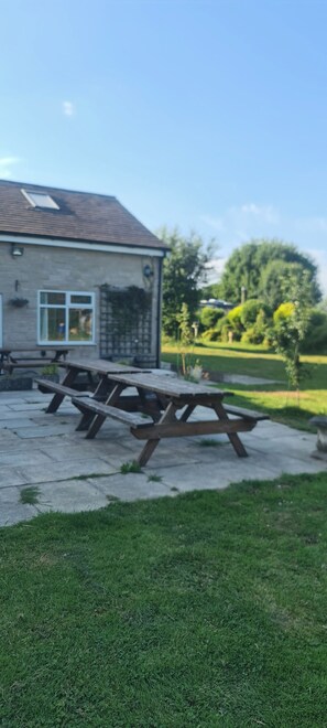 Ein Picknicktisch auf einer Betonplatte, im Hintergrund ein Gebäude.