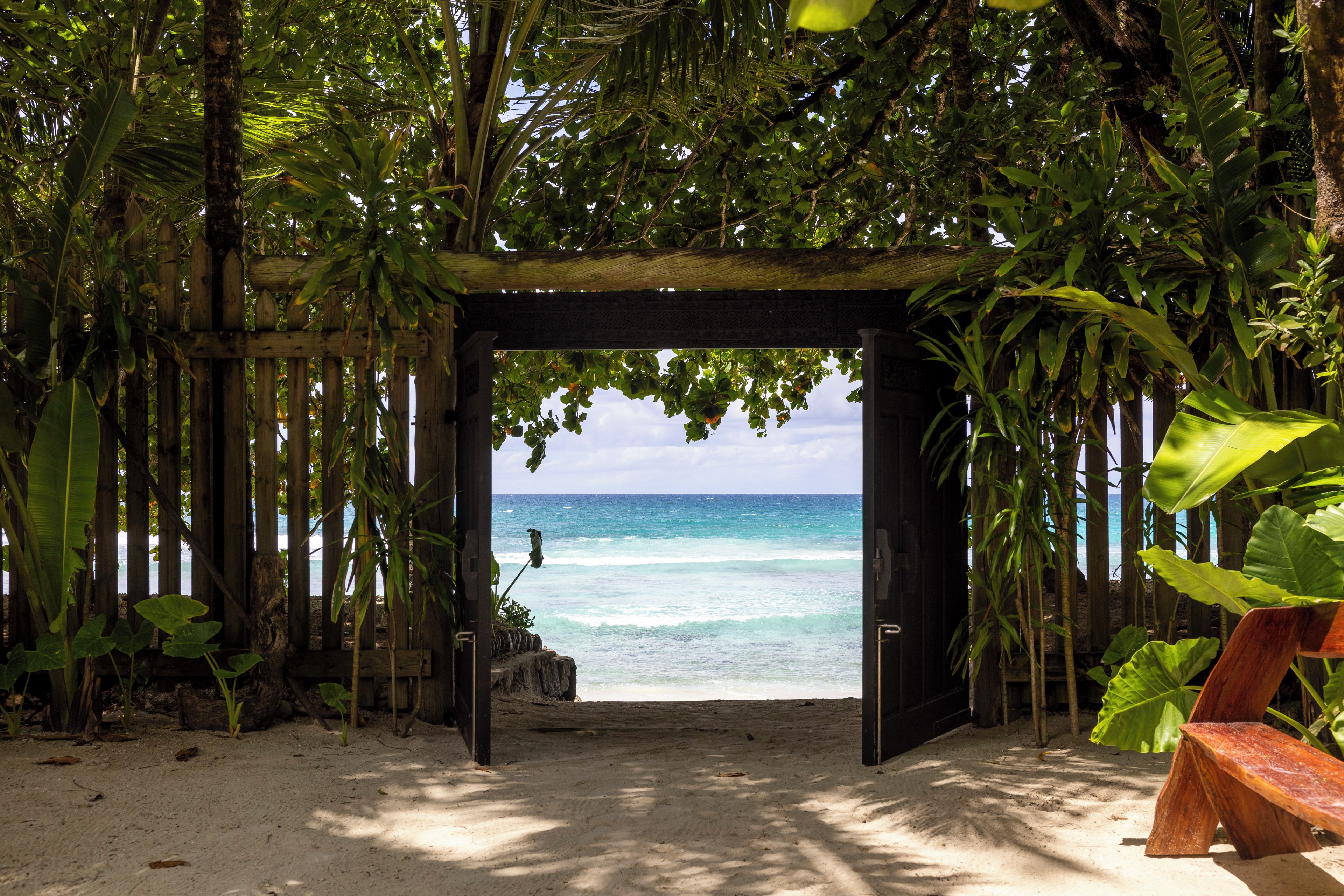 A wooden archway leading to a beach with clear turquoise water.