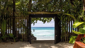 A wooden archway leading to a beach with clear turquoise water.