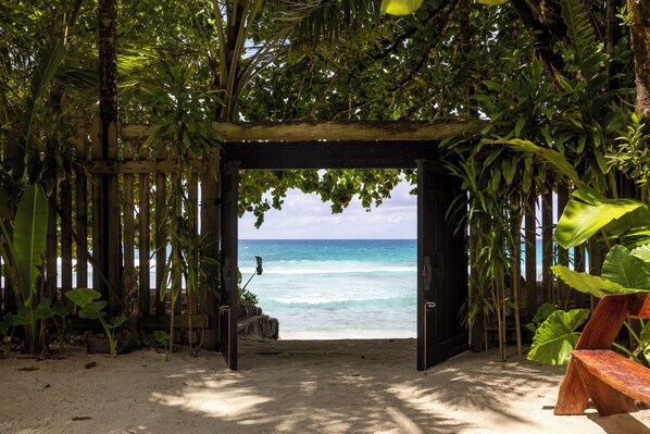 Un arco de madera que da paso a una playa con agua turquesa cristalina.