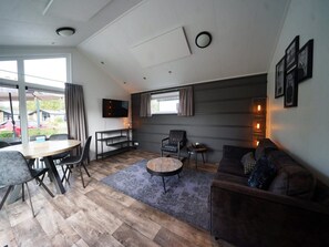 Een moderne woonkamer met een eethoek, een flatscreen televisie en een bank.